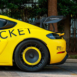 a side view of yellow Porsche gt4rs with silver rocket carbon wing with decals