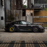 a black Porsche GT4rs with black wheels and silver rocket wing in carbon fiber