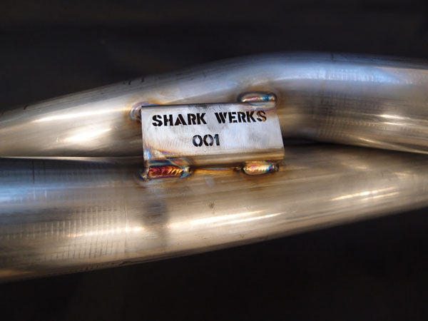 A close up view of Shark Werks Sport Exhaust for Porsche 991 Carrera / S pipes with a black background