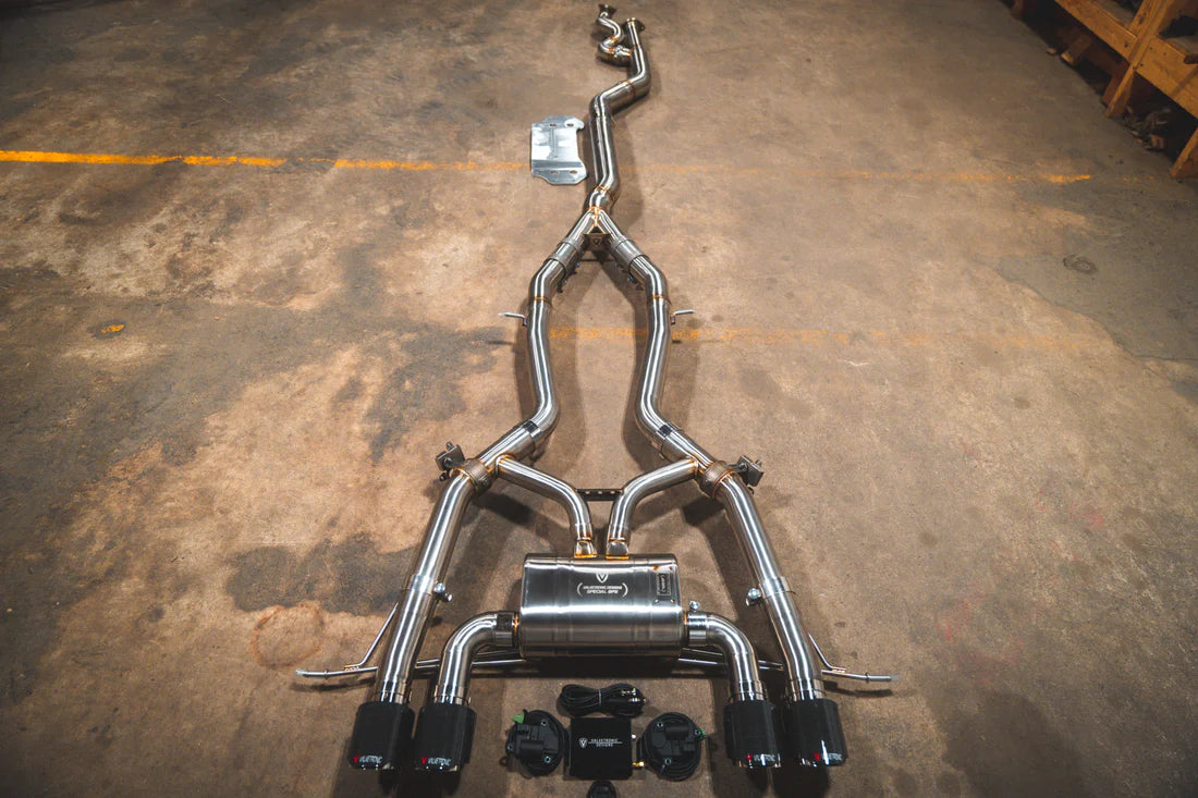 A top overview of Valvetronic Designs Catback Valved Sport Exhaust System with 1x1 Carbon Fiber exhaust tips on the ground (for BMW G8x M3 / M4).