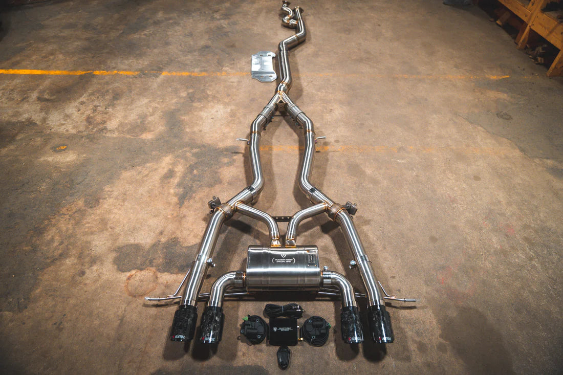 A top overview of Valvetronic Designs Catback Valved Sport Exhaust System with Forged Carbon Fiber exhaust tips on the ground (for BMW G8x M3 / M4).
