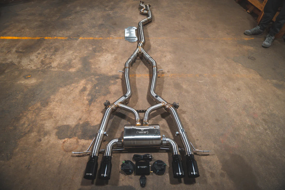 A top overview of Valvetronic Designs Catback Valved Sport Exhaust System with Black exhaust tips on the ground (for BMW G8x M3 / M4).